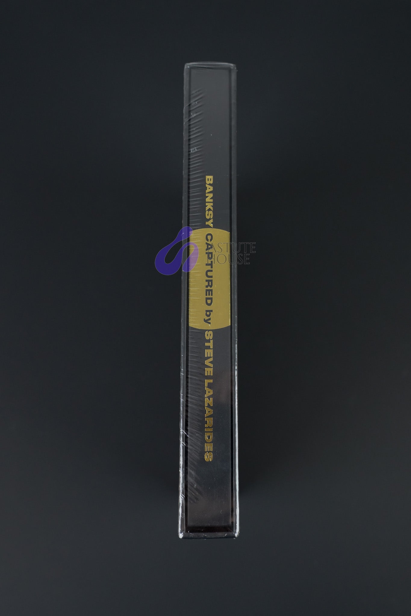 Side profile of the Banksy Captured where gold foil is visible in its hardcover in its black.