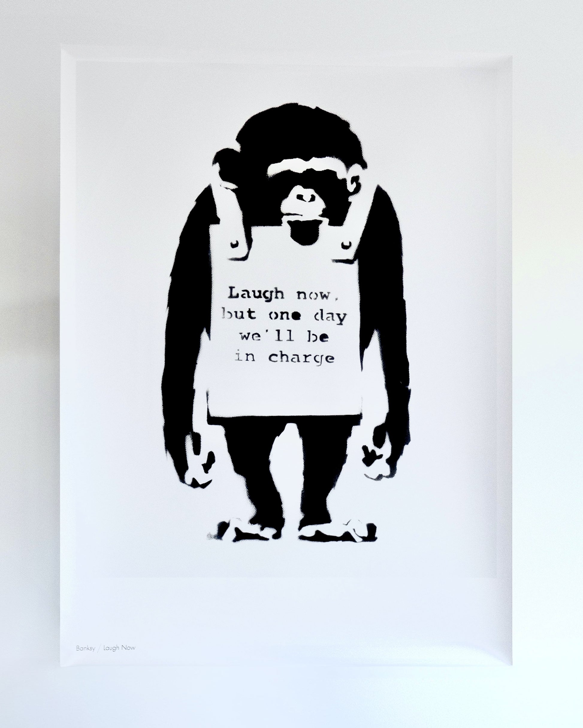 Detailed view of Banksy's 'Laugh Now' print, showcasing the satirical monkey and thought-provoking text.